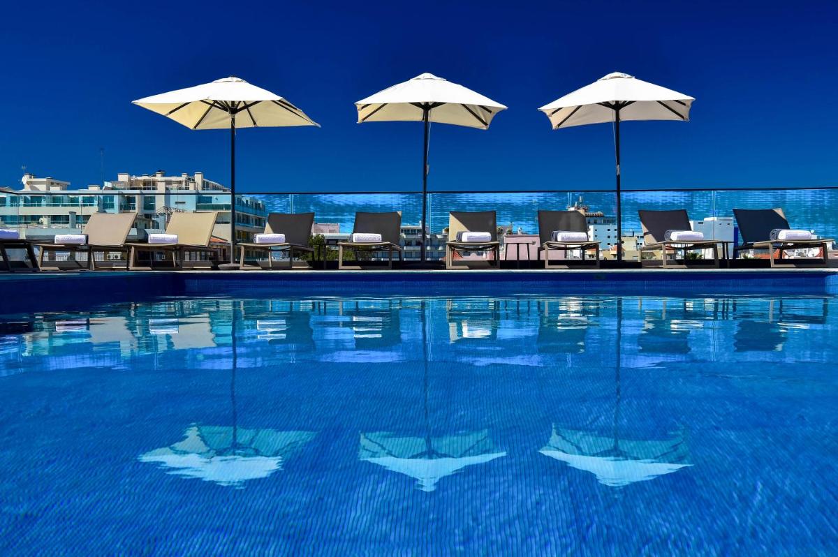 uma piscina com cadeiras e guarda-sóis em The Prime Energize Hotel & SPA - Algarve em Monte Gordo