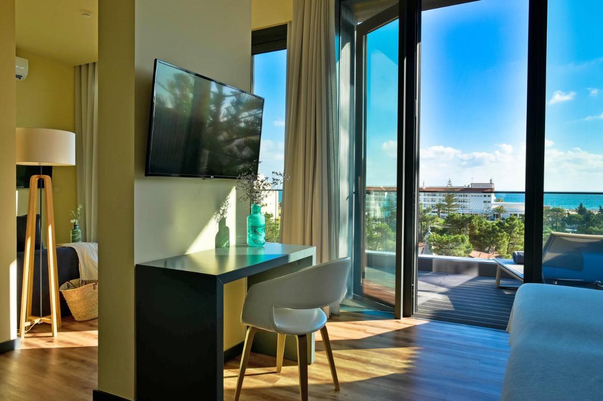 Uma sala de estar com uma escrivaninha e vista para o oceano. em The Prime Energize Hotel & SPA - Algarve em Monte Gordo