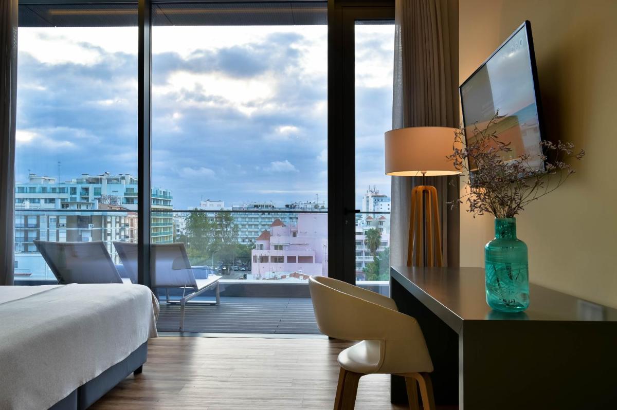 Um quarto de hotel com escrivaninha e uma janela grande. em The Prime Energize Hotel & SPA - Algarve em Monte Gordo