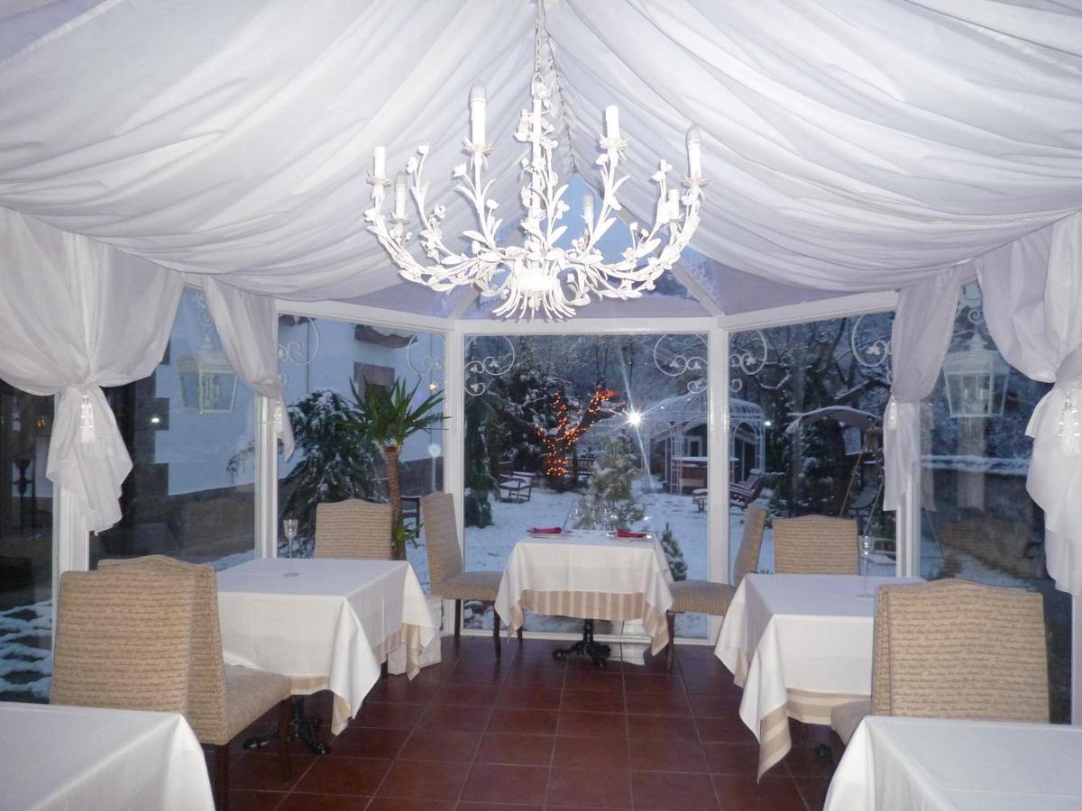 un comedor con mesas blancas y una lámpara de araña en Posada del Indiano, en Cidones