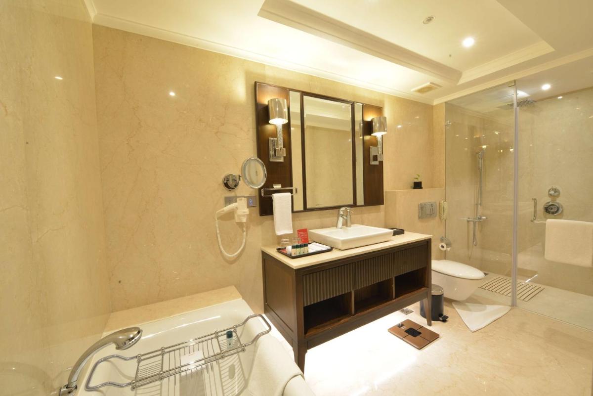 a bathroom with a sink and a toilet and a mirror at Ramada Plaza Chennai in Chennai
