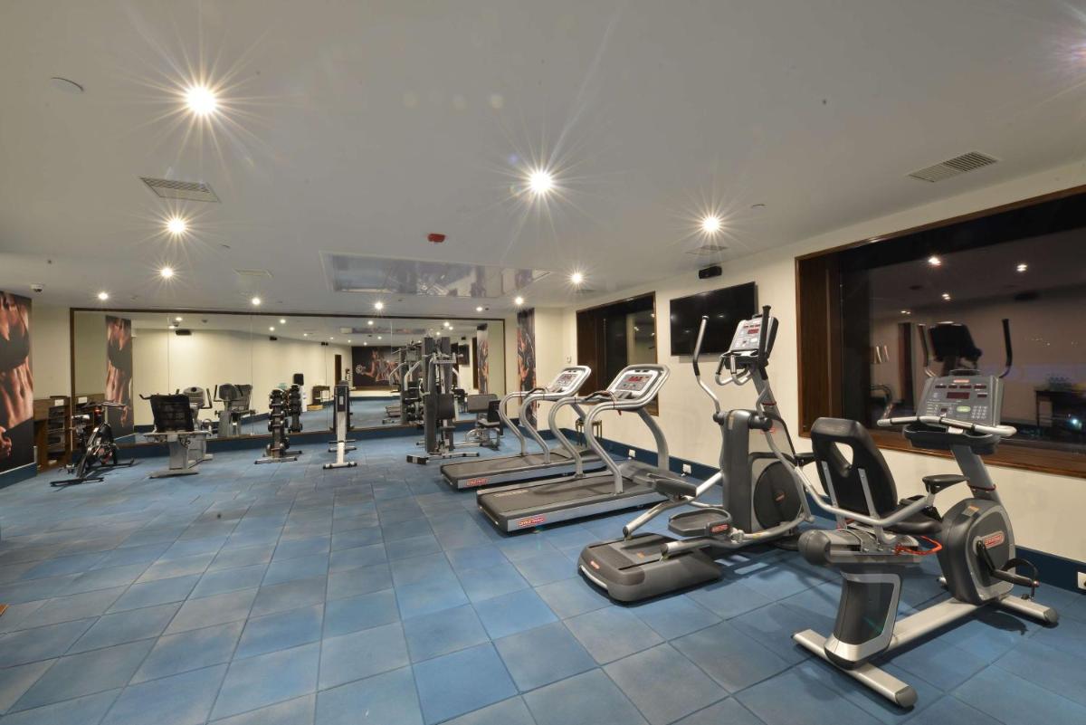 a gym with several treadmills and elliptical machines at Ramada Plaza Chennai in Chennai