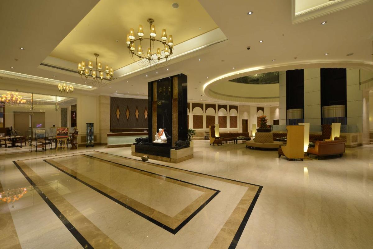 a lobby with a fireplace in the middle of a building at Ramada Plaza Chennai in Chennai