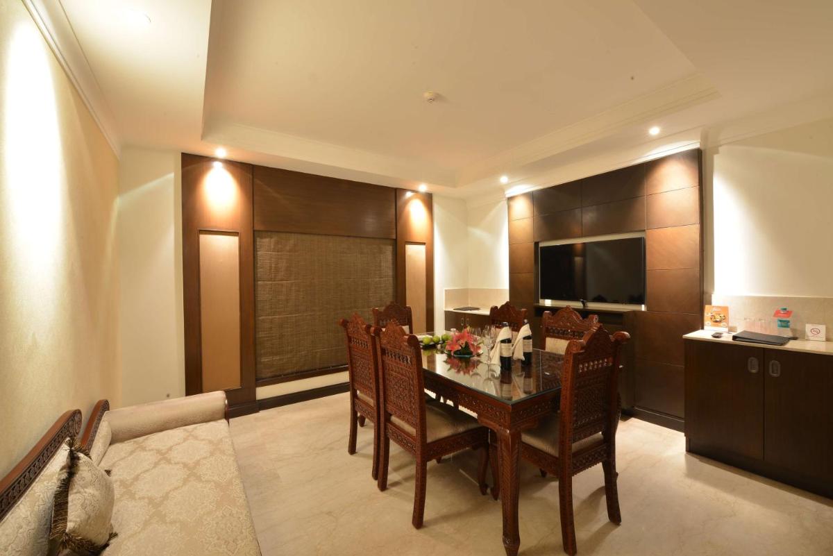 a dining room with a table with chairs and a television at Ramada Plaza Chennai in Chennai