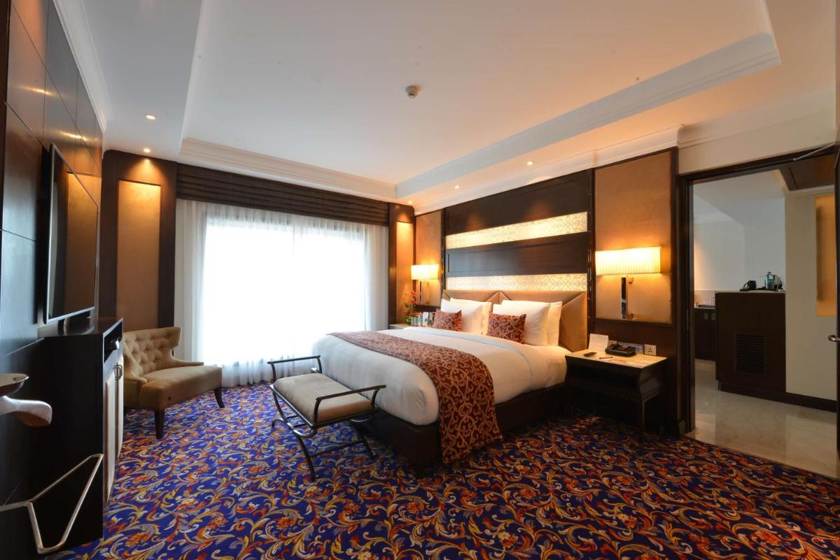 a hotel room with a bed and a television at Ramada Plaza Chennai in Chennai