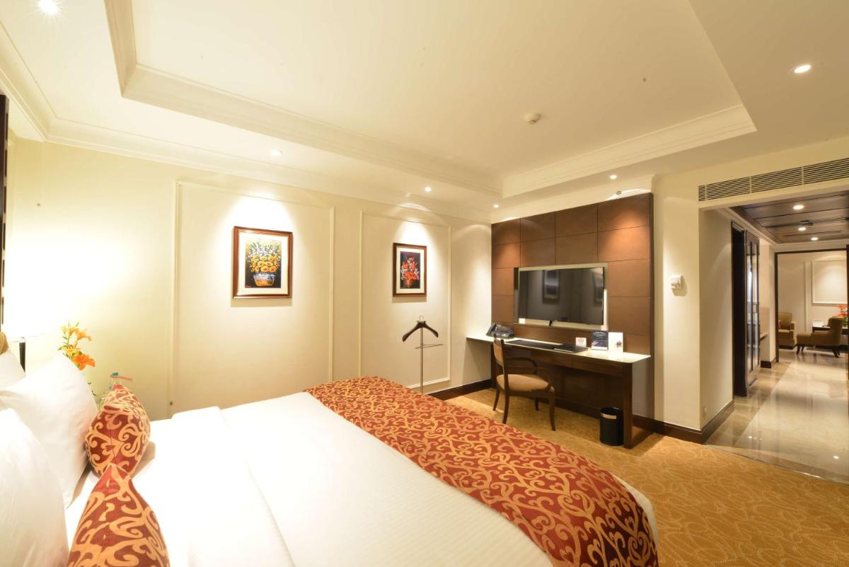 a hotel room with a bed and a desk and a television at Ramada Plaza Chennai in Chennai