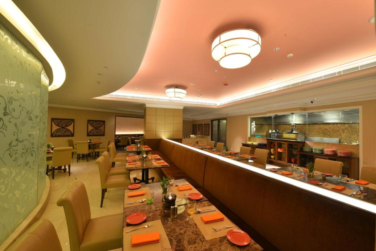 a restaurant with a long bar with tables and chairs at Ramada Plaza Chennai in Chennai