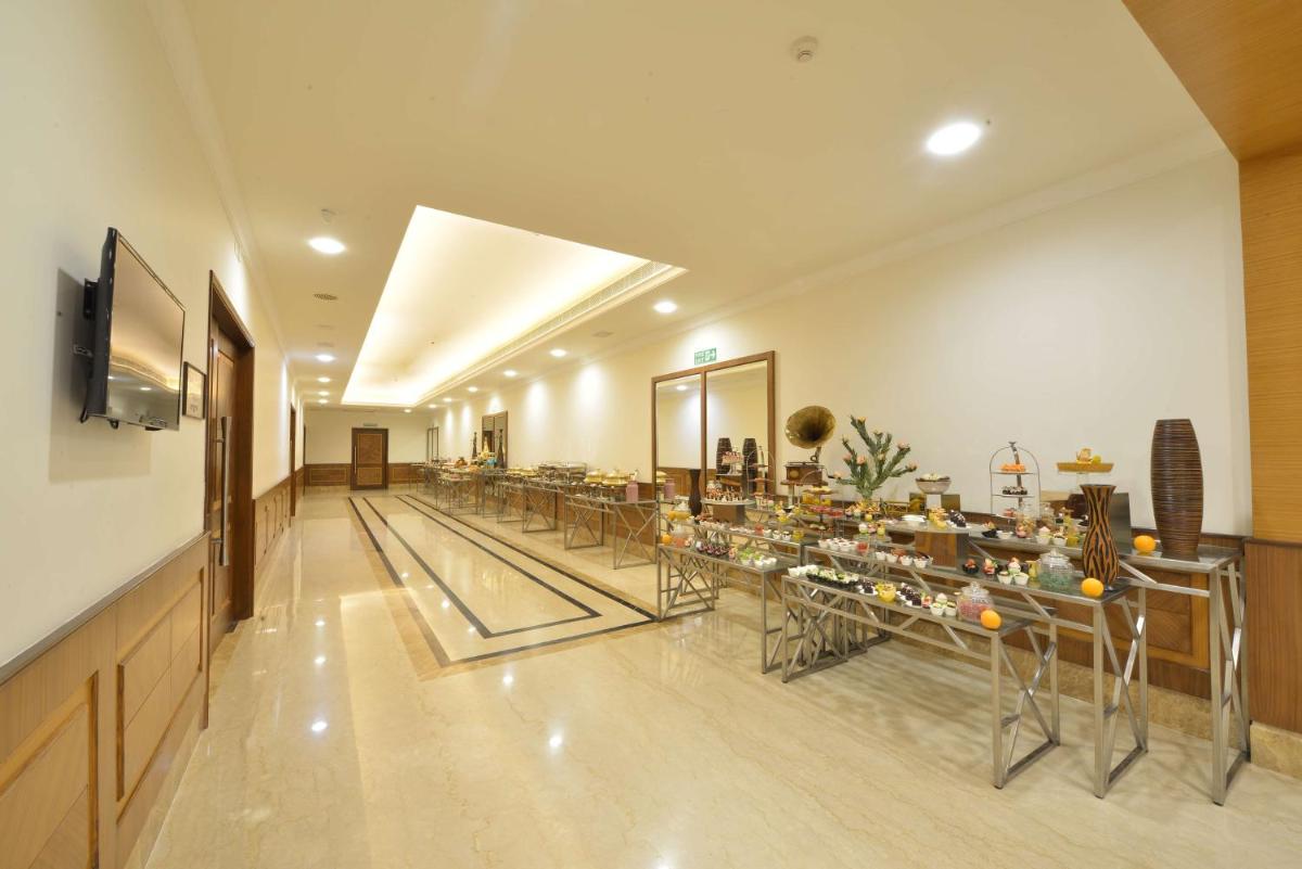 a long hallway with tables and chairs in a building at Ramada Plaza Chennai in Chennai