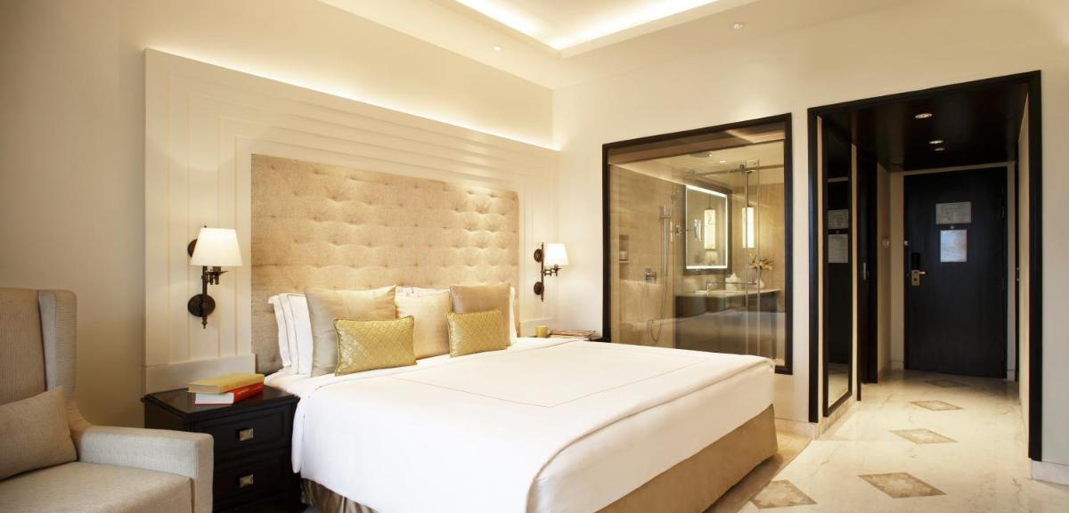 a bedroom with a large white bed and a couch at Taj Ganges Varanasi in Varanasi