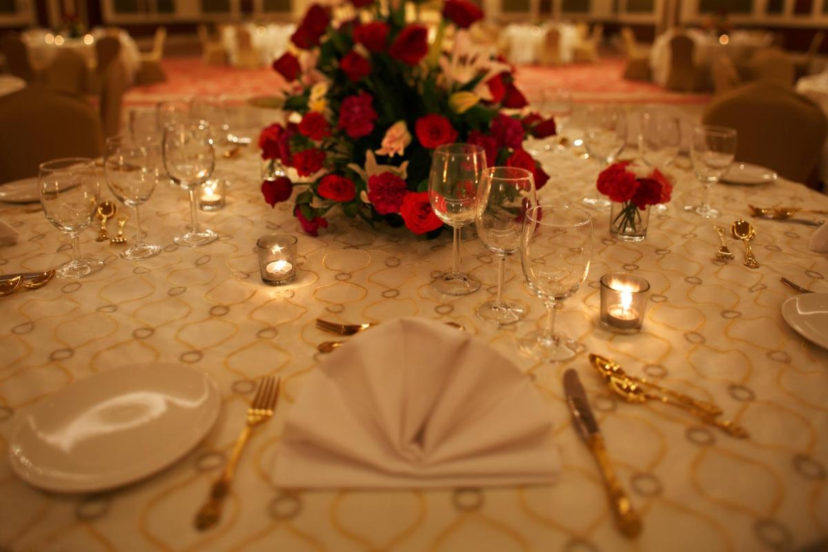 a table with wine glasses and a flower arrangement on it at Taj Ganges Varanasi in Varanasi