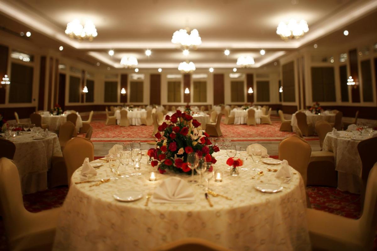a banquet hall with white tables and chairs with a flower arrangement at Taj Ganges Varanasi in Varanasi