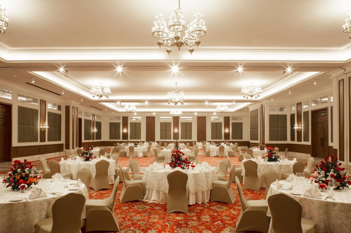 a banquet hall with white tables and chairs and a chandelier at Taj Ganges Varanasi in Varanasi +69 photos