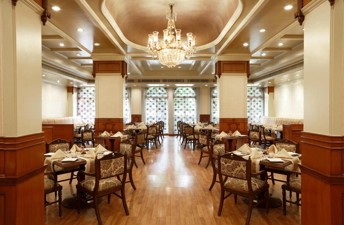 a dining room with tables and chairs and a chandelier at Taj Ganges Varanasi in Varanasi