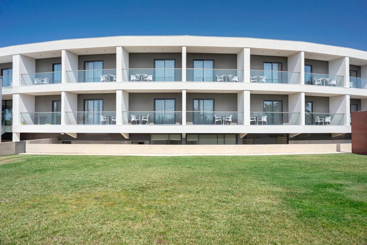 um grande edifício branco com mesas e cadeiras em Hotel dos Zimbros em Sesimbra