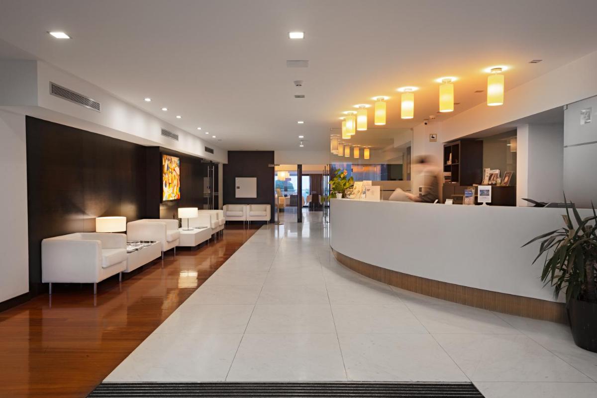 um átrio com cadeiras brancas e um balcão de recepção em Hotel dos Zimbros em Sesimbra um átrio com cadeiras brancas e um balcão de recepção em Hotel dos Zimbros em Sesimbra