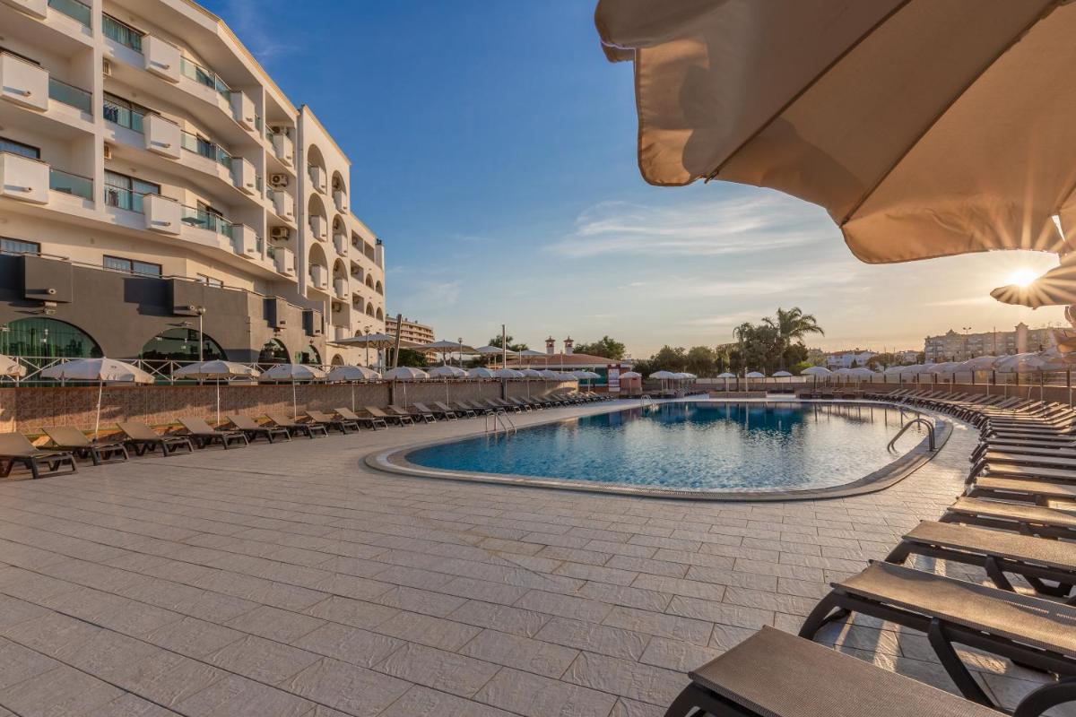 uma piscina num resort com cadeiras e um edifício em The Navigator - Solaqua em Albufeira uma piscina num resort com cadeiras e um edifício em The Navigator - Solaqua em Albufeira