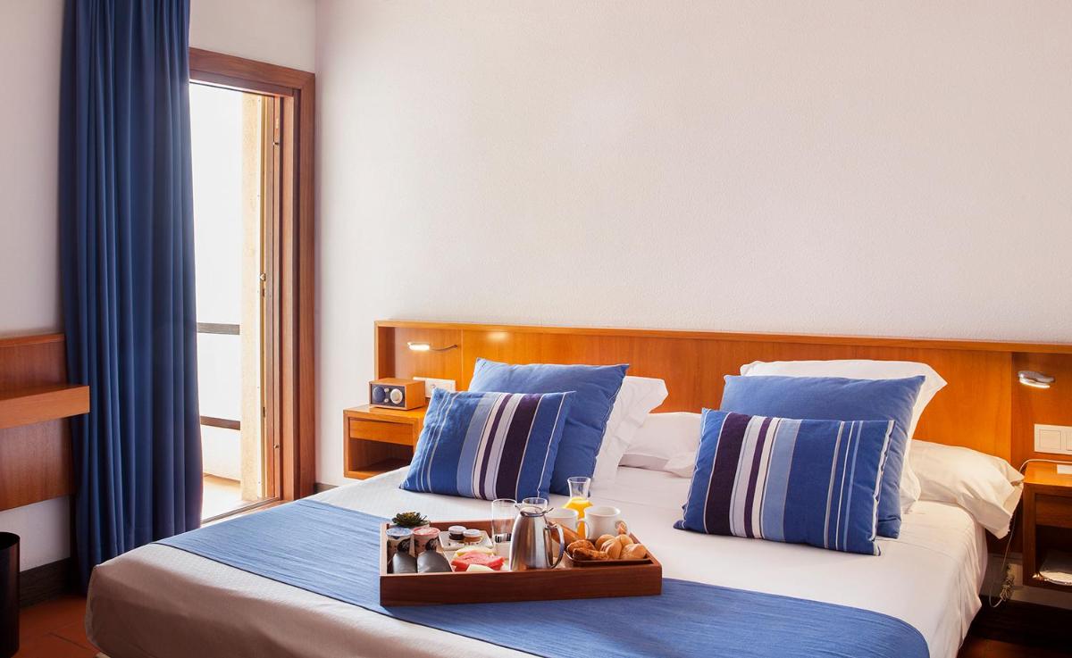 Una habitación de hotel con una cama con una bandeja de comida encima. en Almadraba Park Hotel, en Roses