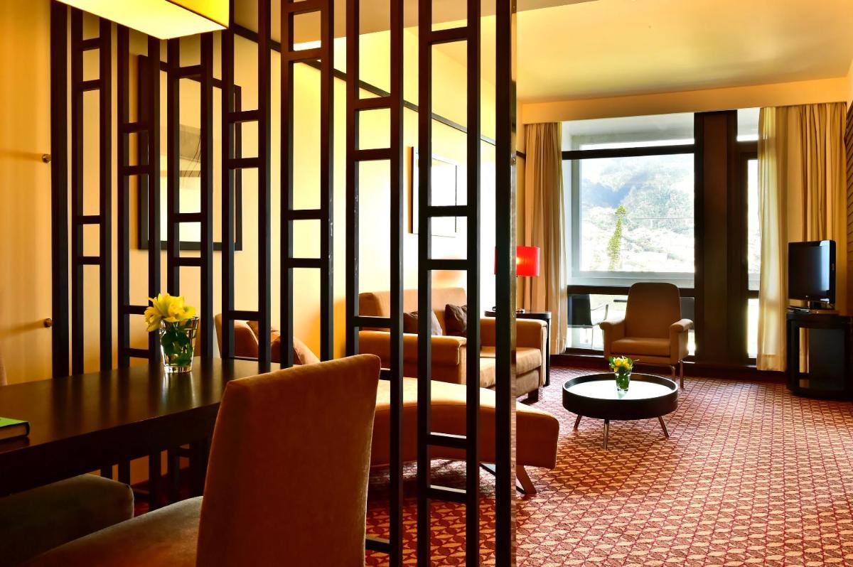 um quarto de hotel com uma mesa e cadeiras e uma sala de estar em Pestana Casino Park Hotel & Casino no Funchal