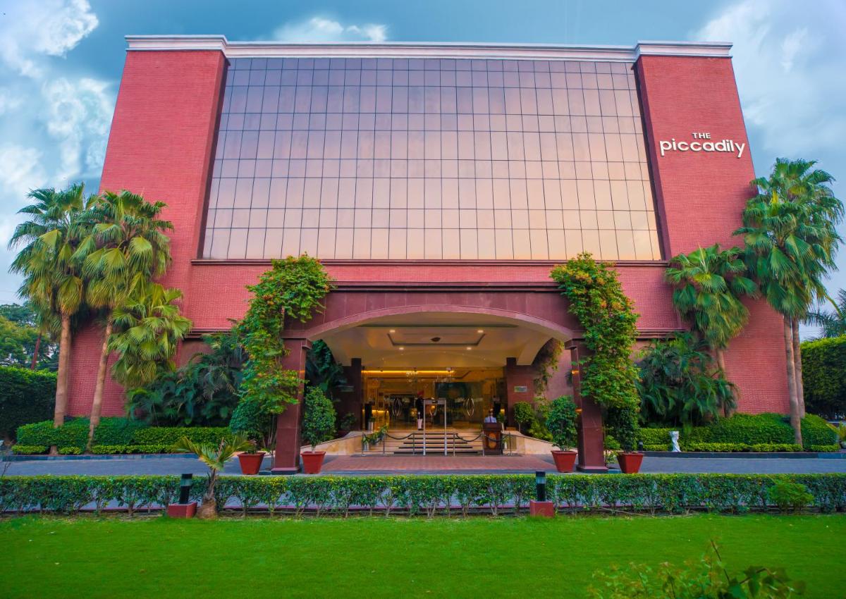 a large red building with palm trees in front of it at The Piccadily in Lucknow