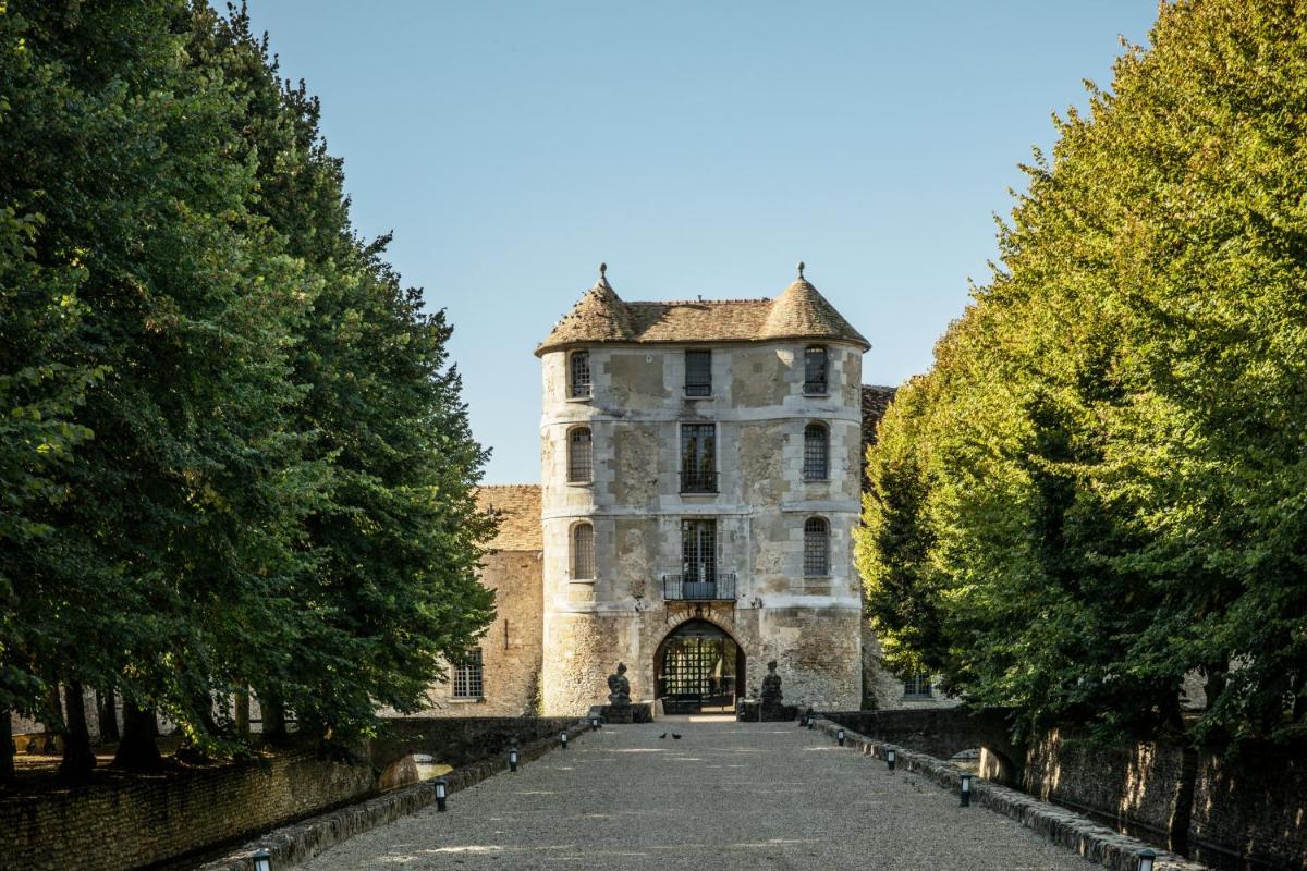 un vieux château avec des arbres devant dans l'établissement Château De Villiers-Le-Mahieu, à Villiers-le-Mahieu