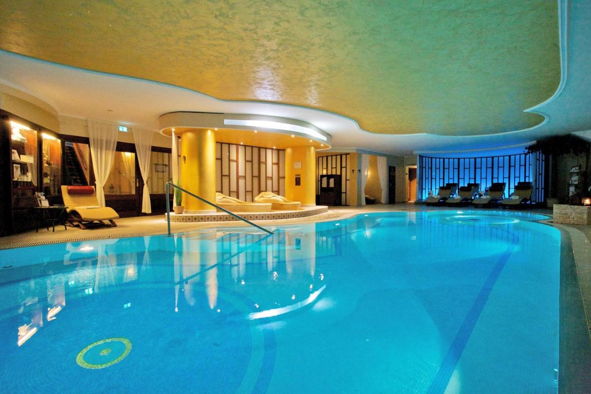 ein großer blauer Pool in einem Hotel in der Unterkunft SEETELHOTEL Ahlbecker Hof das elegante Traditionshotel & ruhiger Rückzugsort an der Ostsee in Ahlbeck
