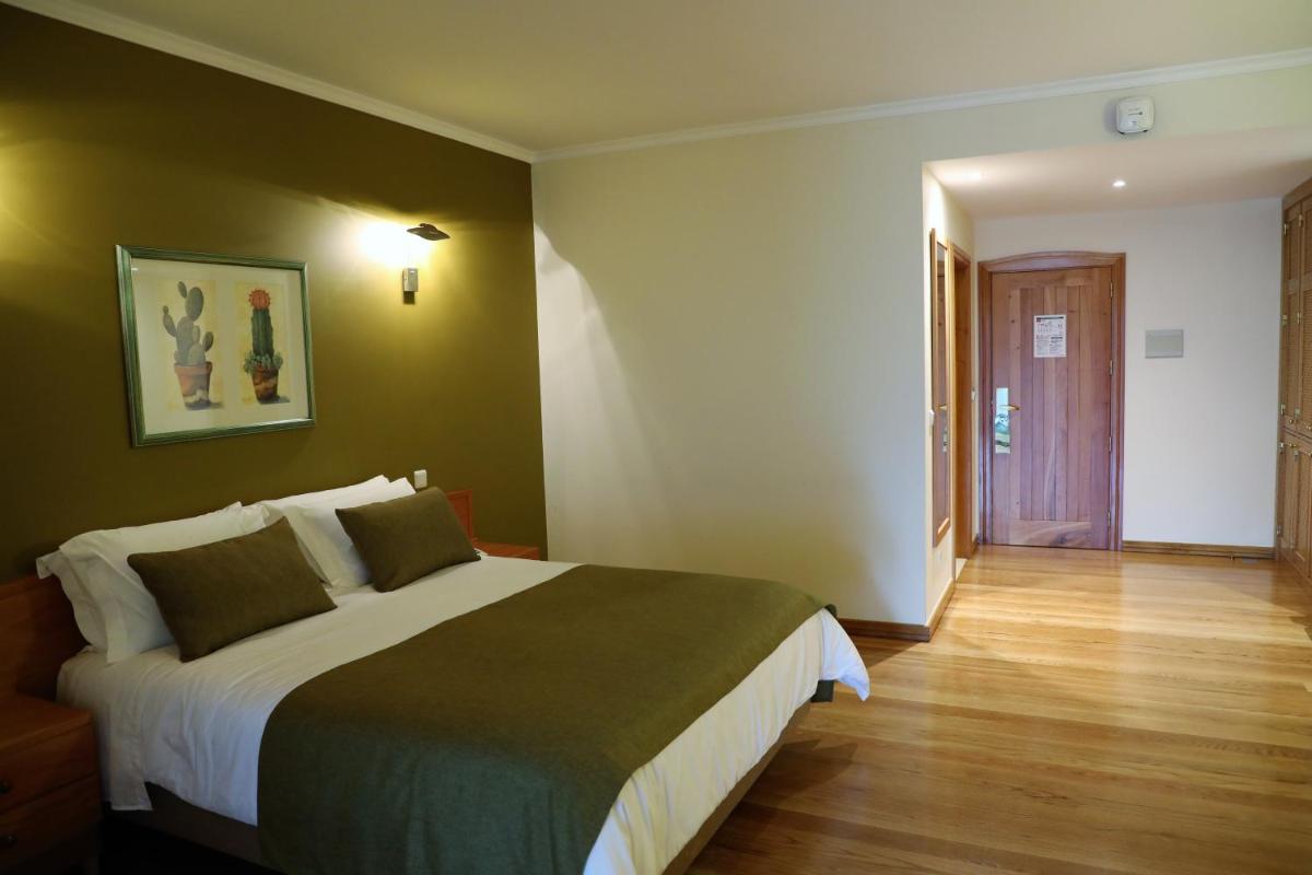 um quarto com uma cama grande e piso de madeira em Eira do Serrado - Hotel & Spa em Curral das Freiras mais 61 fotografias