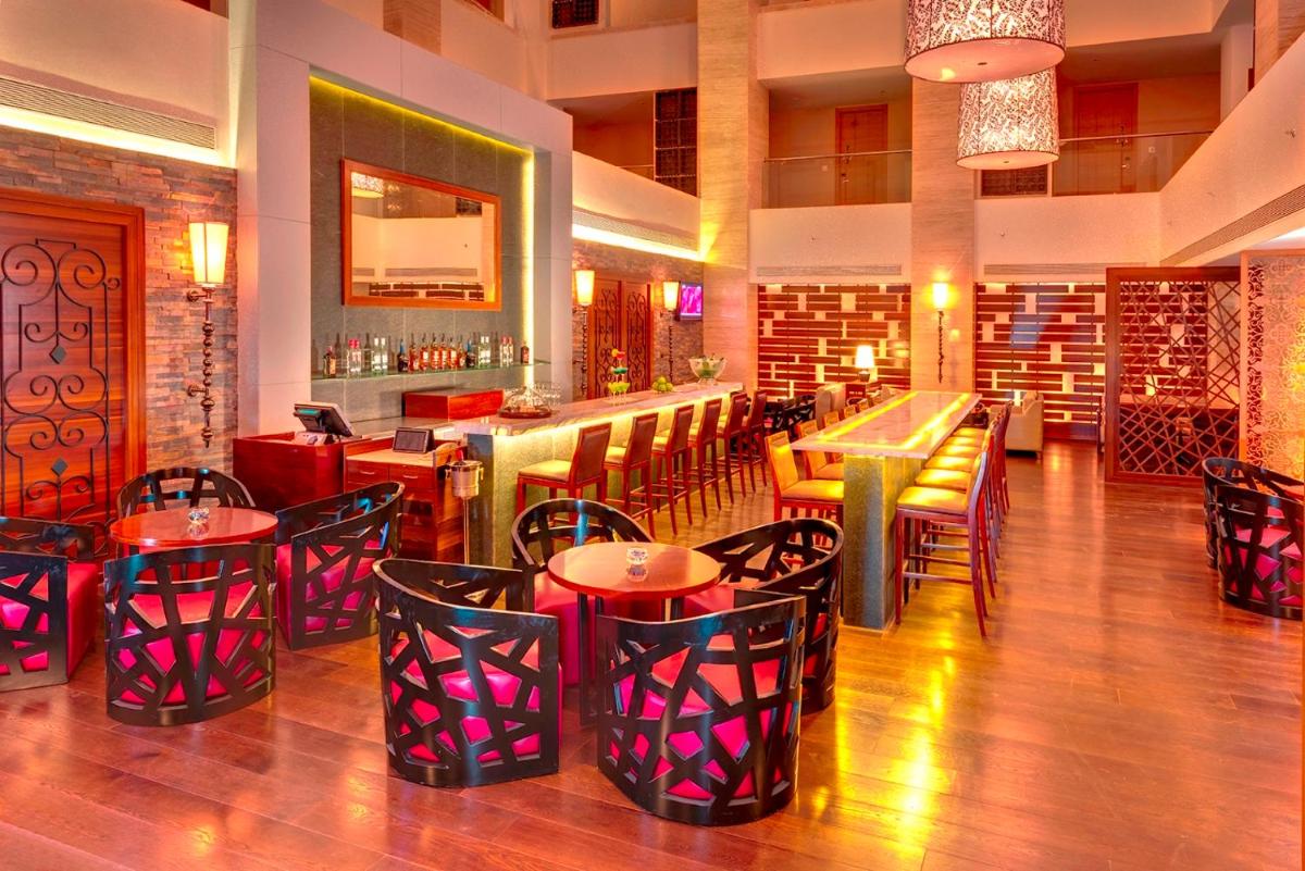 a restaurant with tables and chairs and a bar at Pride Plaza Hotel, Kolkata in Kolkata