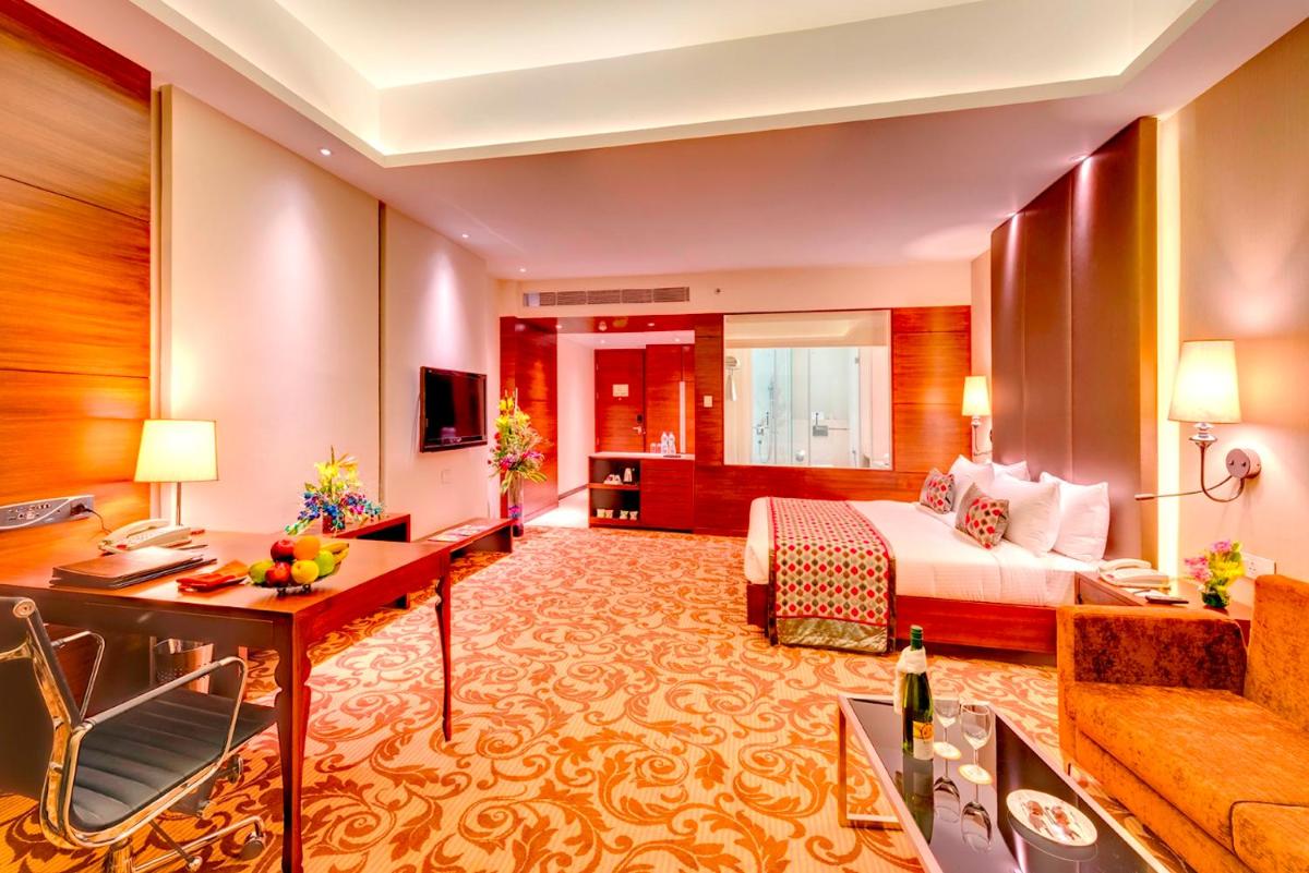 a hotel room with a bed and a desk at Pride Plaza Hotel, Kolkata in Kolkata
