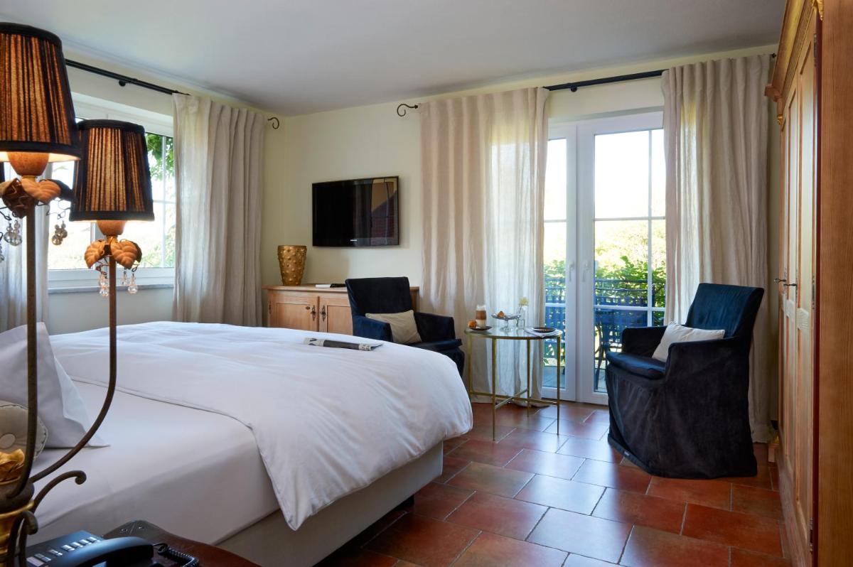 ein Schlafzimmer mit einem großen Bett und zwei Stühlen in der Unterkunft Hotel VILLINO in Lindau