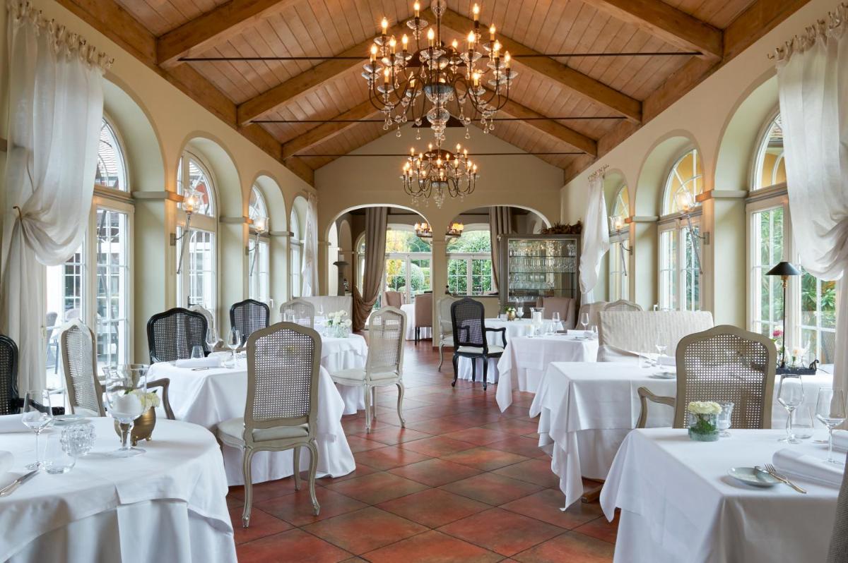 ein Restaurant mit weißen Tischen und Stühlen und einem Kronleuchter in der Unterkunft Hotel VILLINO in Lindau