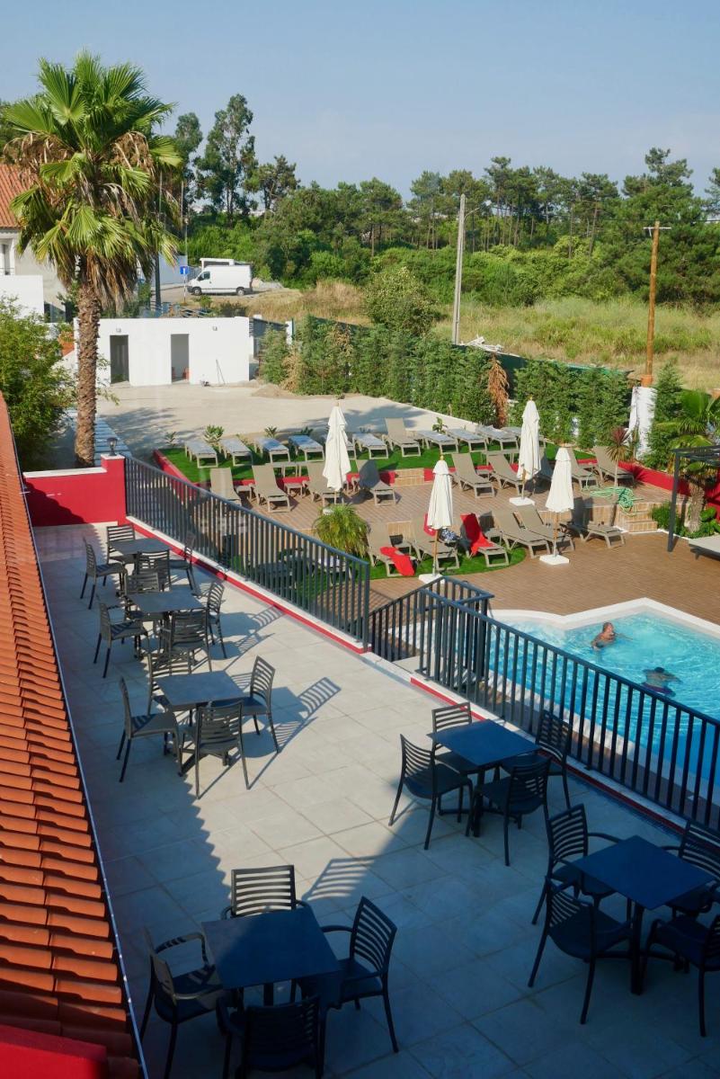uma piscina com mesas e cadeiras ao lado de uma piscina em Villa 3 Caparica - Lisbon Gay Beach Resort em Charneca