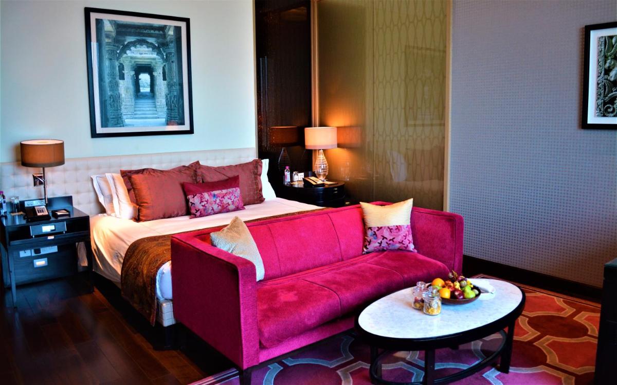 a room with a bed and a red couch at Taj Santacruz in Mumbai