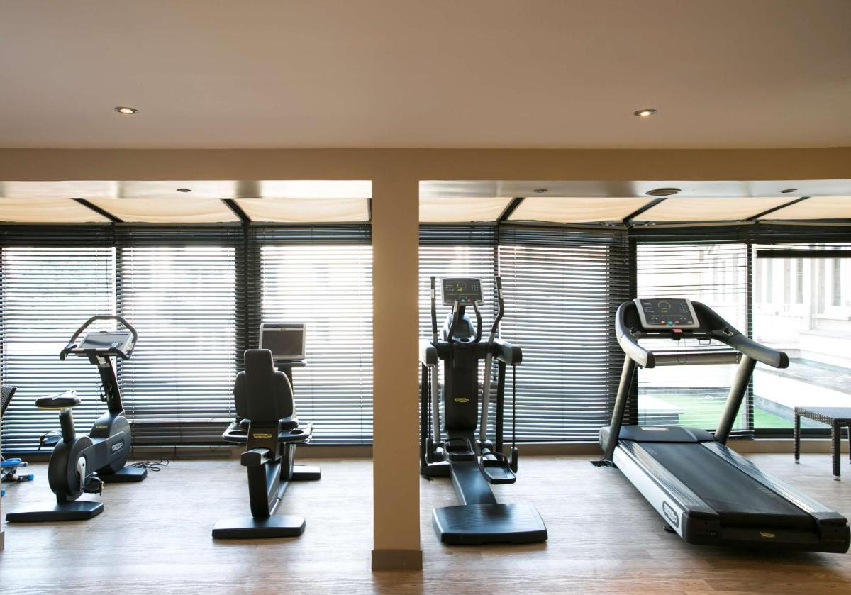 une salle de sport avec plusieurs tapis de course et machines elliptiques dans l'établissement Hotel & Spa Le Grand Monarque, BW Premier Collection, à Chartres