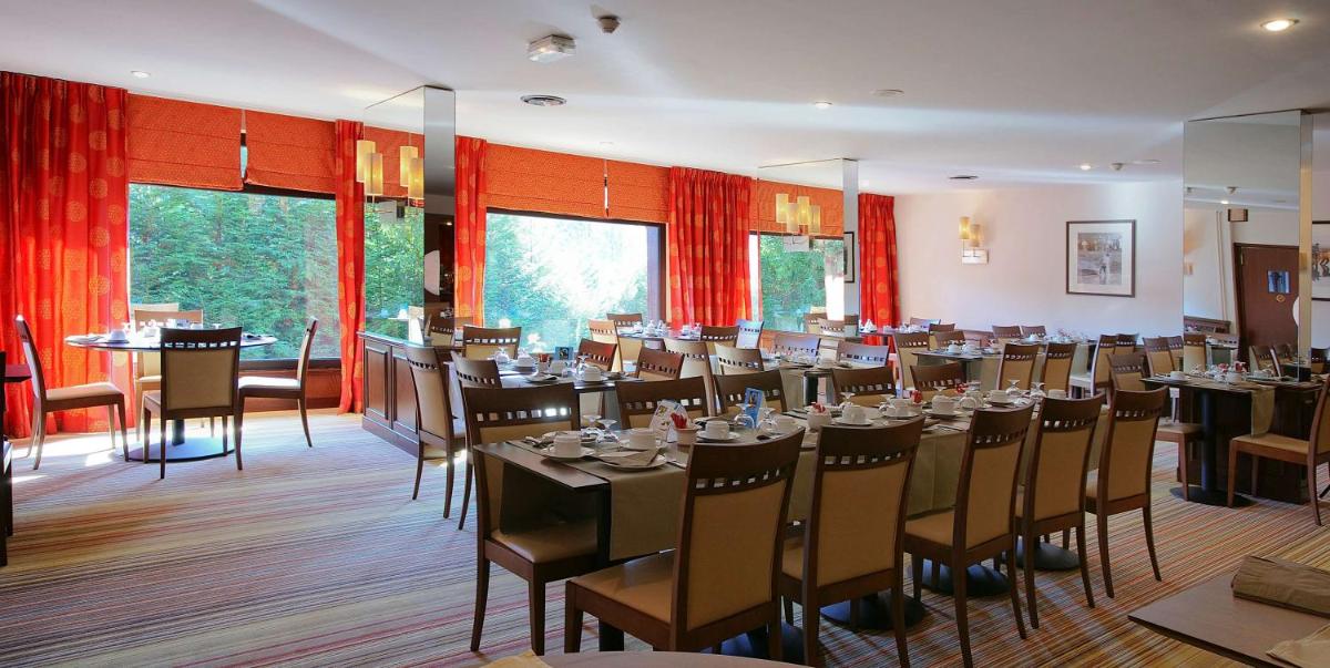 une salle à manger avec des tables, des chaises et des rideaux rouges dans l'établissement Best Western Plus Hostellerie Du Vallon, à Trouville-sur-Mer