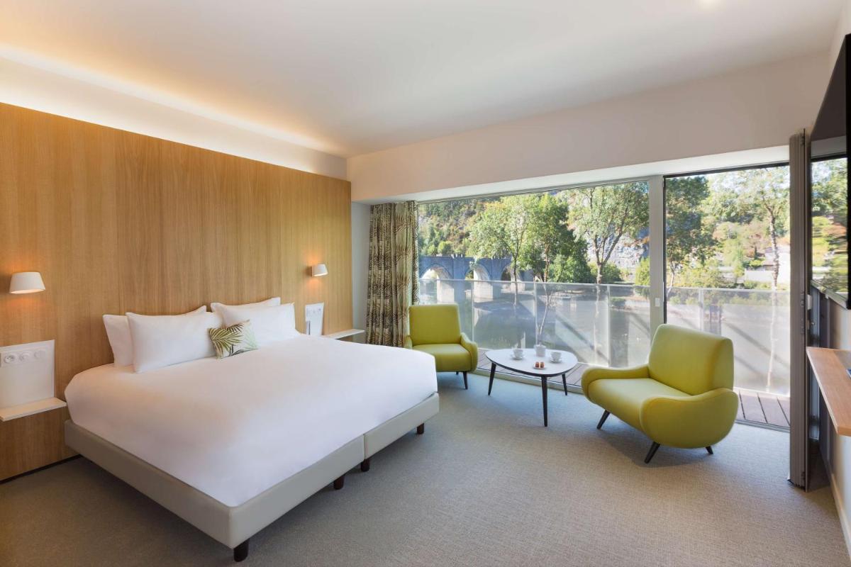 une chambre d'hôtel avec un lit et une grande fenêtre dans l'établissement Best Western Plus Hotel Divona Cahors, à Cahors