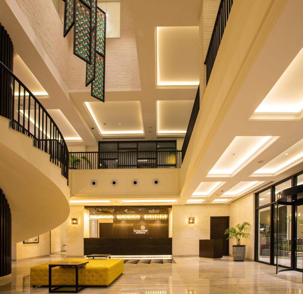 a lobby of a hotel with a yellow couch and stairs at Lemon Tree Premier City Center Pune in Pune