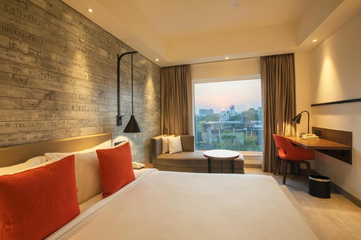 a hotel room with a bed and a desk at Lemon Tree Premier City Center Pune in Pune