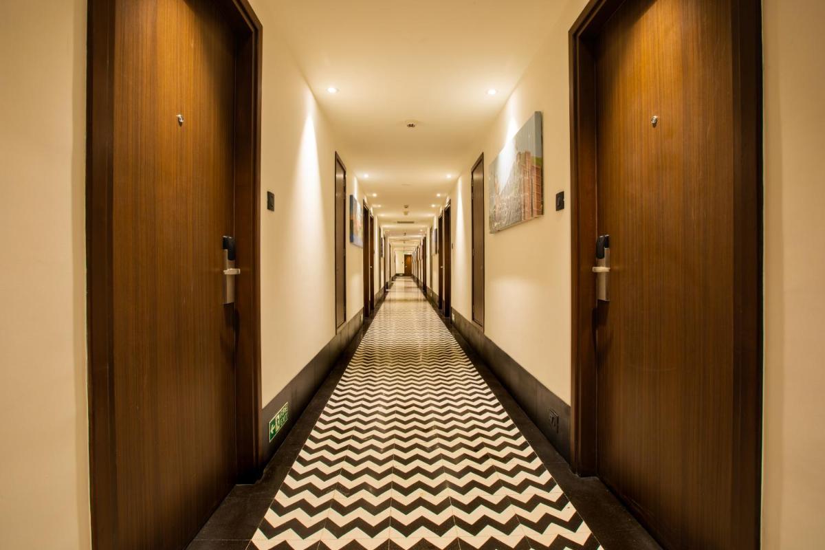 a hallway with a long corridor with black and white flooring at Lemon Tree Premier City Center Pune in Pune