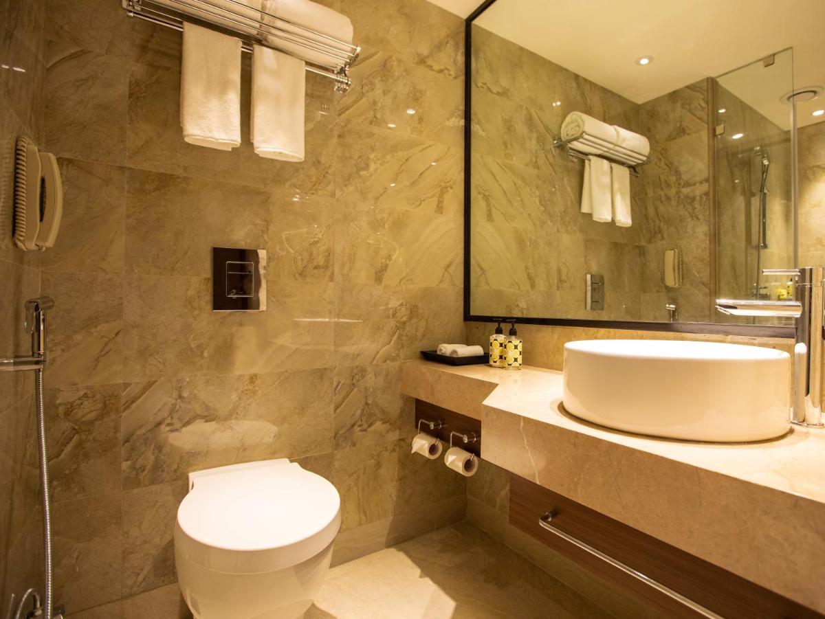 a bathroom with a sink and a toilet and a mirror at Lemon Tree Premier City Center Pune in Pune