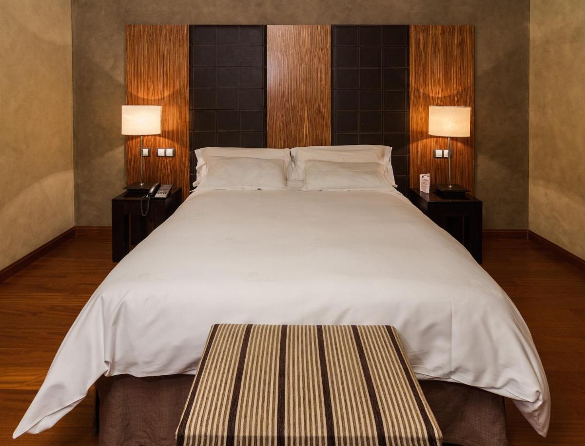 1 cama blanca grande con 2 mesitas de noche y 2 lámparas en Hotel & Spa La Salve, en Torrijos