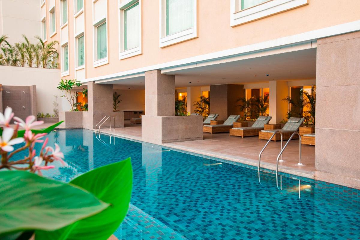 a swimming pool in front of a building at Lemon Tree Premier City Center Pune in Pune