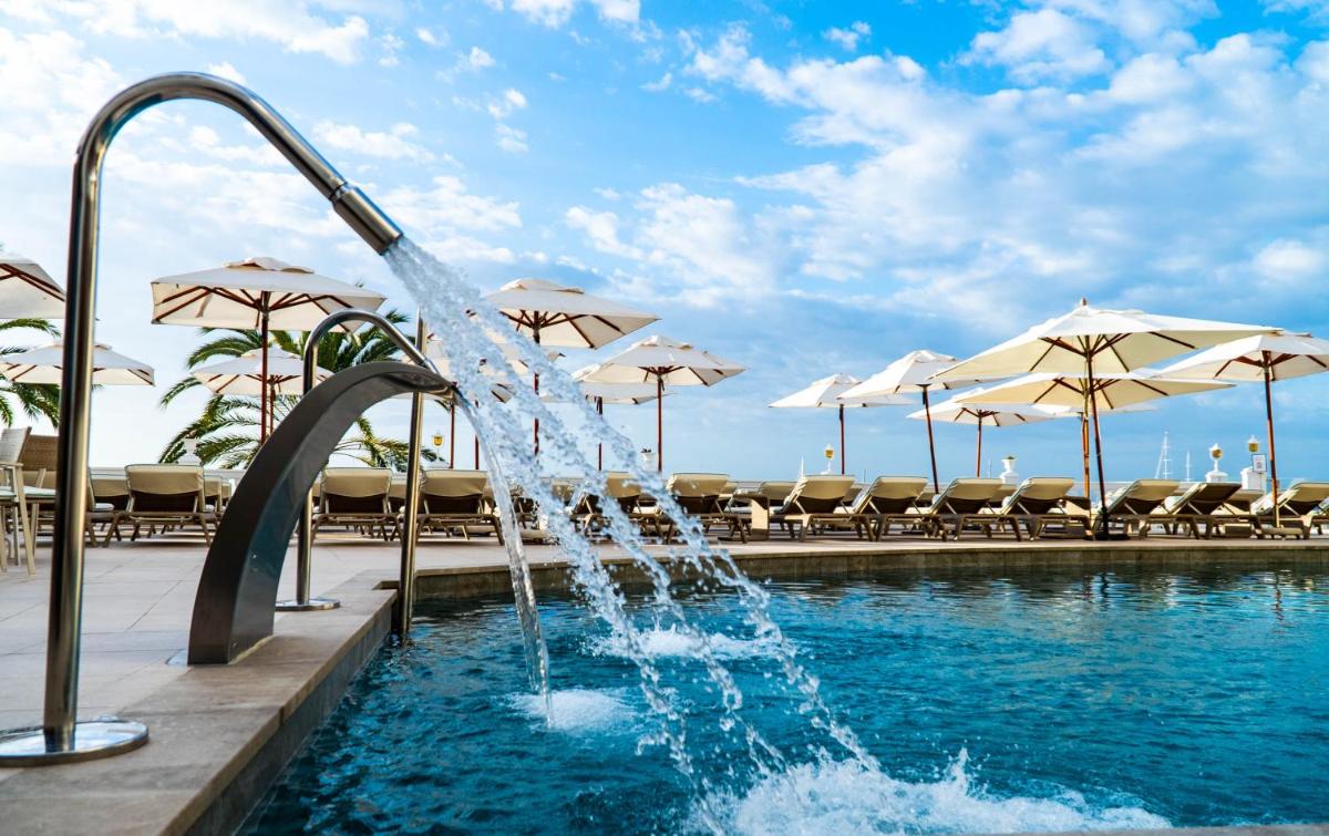 una fuente de agua en una piscina con sombrillas en Nixe Palace, en Palma de Mallorca