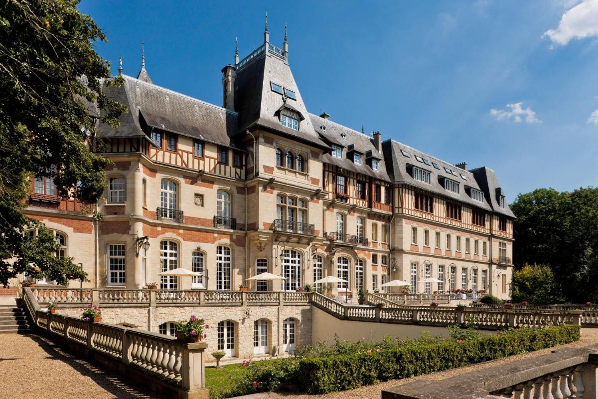 un grand bâtiment avec une clôture devant dans l'établissement Château Jeanne & The Forest - Château de Montvillargenne, à Gouvieux
