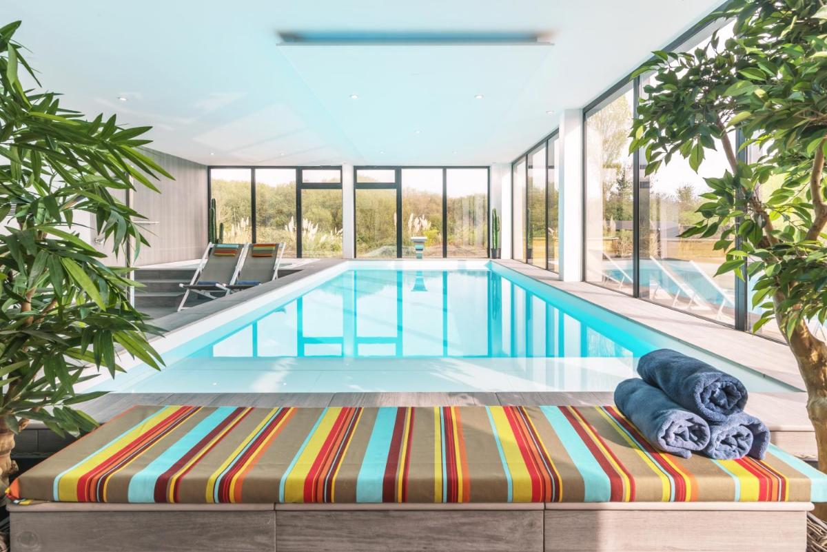une piscine intérieure avec une grande paroi en verre dans l'établissement Carnac Lodge Hotel & Spa, à Plouharnel