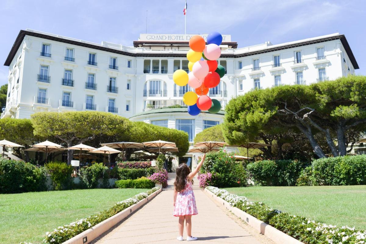 une petite fille tenant des ballons devant un bâtiment dans l'établissement Grand-Hôtel du Cap-Ferrat, A Four Seasons Hotel, à Saint-Jean-Cap-Ferrat