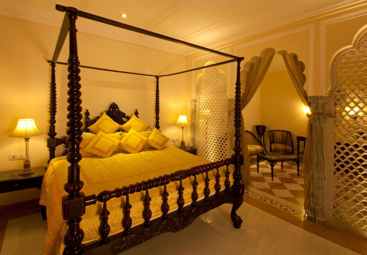 a bedroom with a canopy bed and a chair at Shahpura House in Jaipur