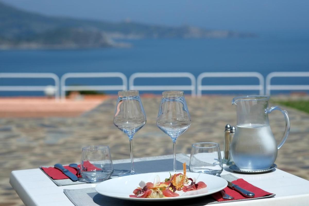 une table avec une assiette de nourriture et des verres à vin dans l'établissement Le Catalan, à Banyuls-sur-Mer