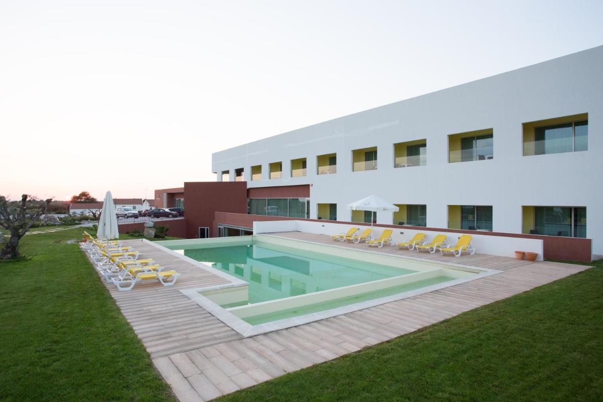 um hotel com piscina e cadeiras e um prédio em Monte Filipe Hotel no Alpalhão