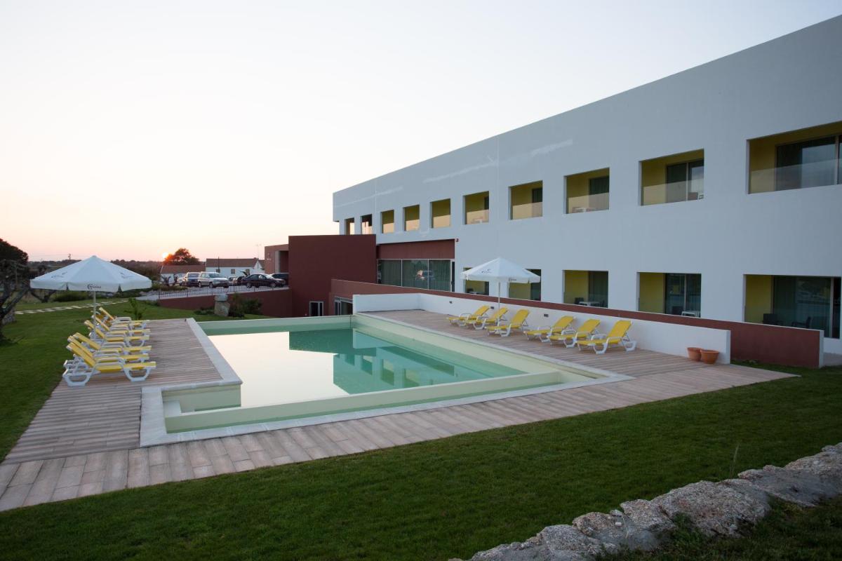 um edifício com piscina e espreguiçadeiras em Monte Filipe Hotel no Alpalhão