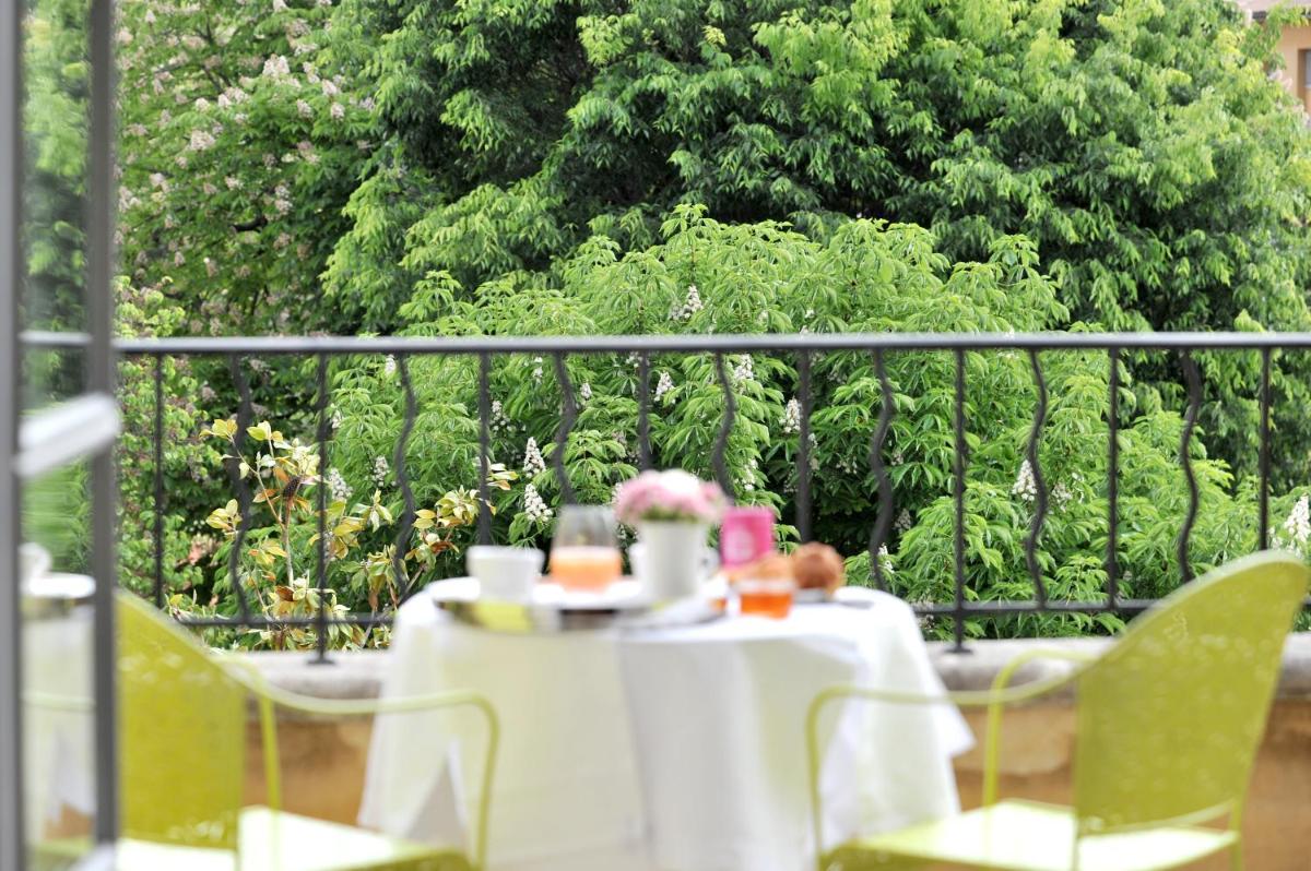 - une table avec un chiffon de table blanc et des fleurs sur un balcon dans l'établissement La Maison d'Aix 1785 - Hôtel Particulier & Spa, à Aix-en-Provence
